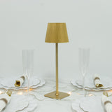 Gold pleated table lamp on a dining table with elegant glassware and plates.