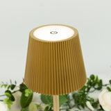 Gold ribbed lamp with a power button on a white background.