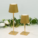 Gold pleated lamps in two sizes on a marble surface with greenery backdrop.