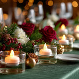 Decorative candles on a festive table with red roses and holiday greenery.