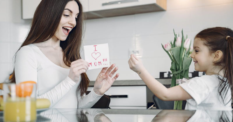 Mother and daughter exchanging a handmade Mother's Day card