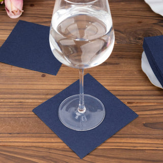 Navy blue coasters under a glass of water on a wooden table.