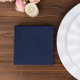 Navy blue square box on a wooden table with flowers and a candle.