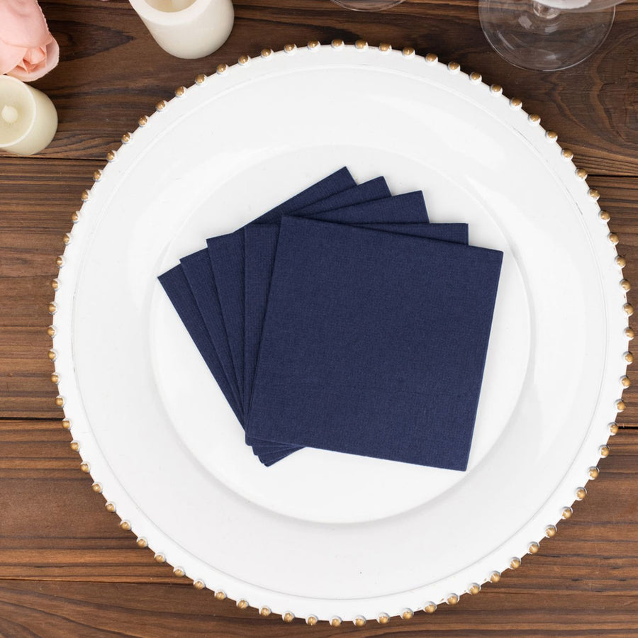 Navy blue napkins stacked on a decorative plate.