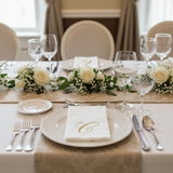 Elegant dinner table setting with white roses and fine dining utensils.