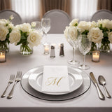 Elegant table setting with white roses, crystal glasses, and monogrammed napkin.