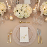Elegant table setting with white floral centerpiece and gold-accented dinnerware.
