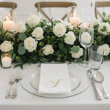 Elegant table setting with white roses, candles, and glassware.