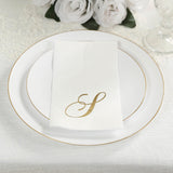 Elegant white plate with gold trim and personalized napkin on a textured tablecloth.