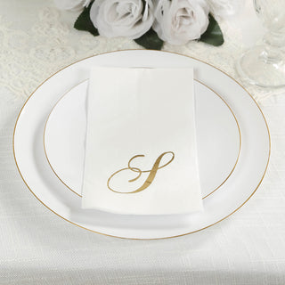 Elegant white plate with gold trim and personalized napkin on a textured tablecloth.