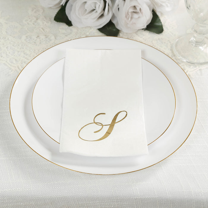 Elegant white plate with gold trim and personalized napkin on a textured tablecloth.
