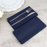 Navy blue napkins with silver fork and knife on a neutral surface.