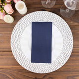 Elegant table setting with textured charger plate and navy napkin.