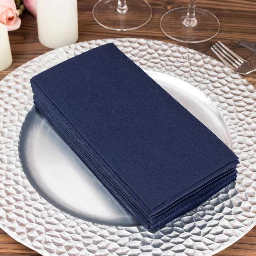Navy blue napkins stacked on a decorative silver plate.