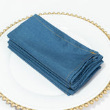 Folded blue napkins stacked on a decorative plate.