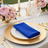 Elegant blue napkin on a gold charger plate at a beautifully set table.