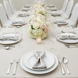 Elegant dining table setup with floral centerpiece and silver napkin accents.