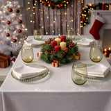 Festive holiday dining table set with candles, greenery, and decorative elements.