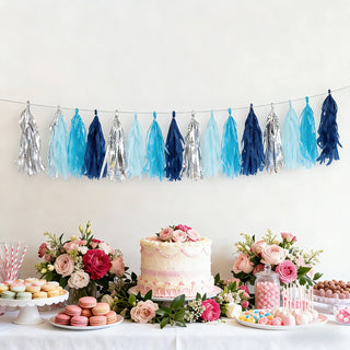 Party decoration with blue and silver tassels above a dessert table.