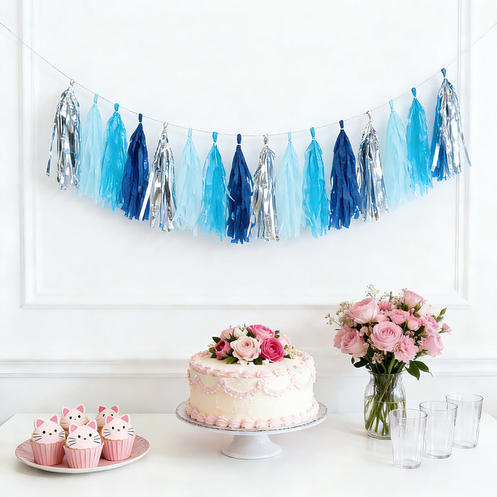 Blue and silver tassel garland with cake and cupcakes on a white background.