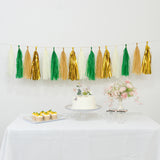 Colorful tassel garland decoration with cake, cupcakes, and flowers on a table.