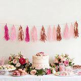 Colorful tassel garland above a dessert table with cake, flowers, and treats.