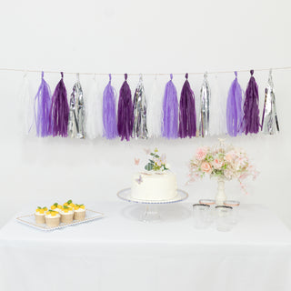Party decoration with purple and silver tassels, cake, and cupcakes on a table.