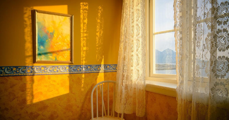 Sunlit room with lace curtains and framed art