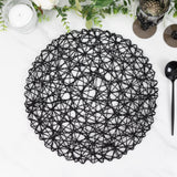 Black woven placemat on a marble surface with decorative elements around it.