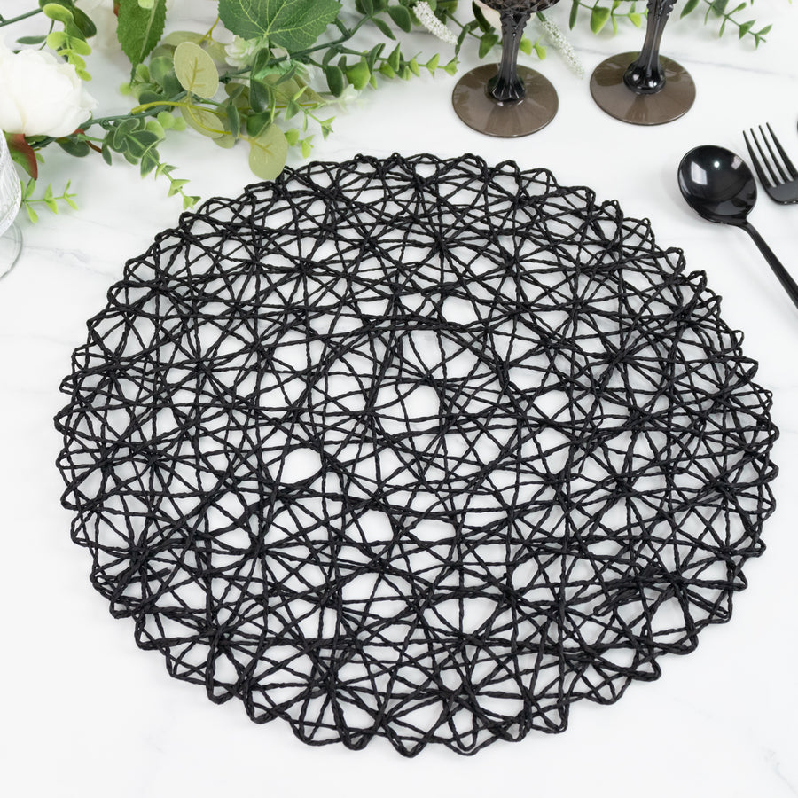 Black woven round placemat with intricate design on a marble table.