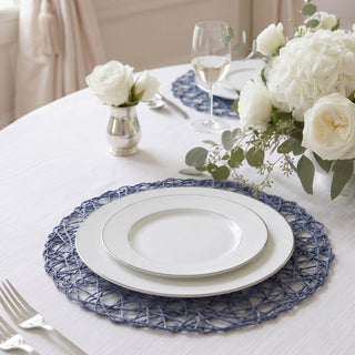 Elegant white dinner plates with blue woven placemat and floral table setting