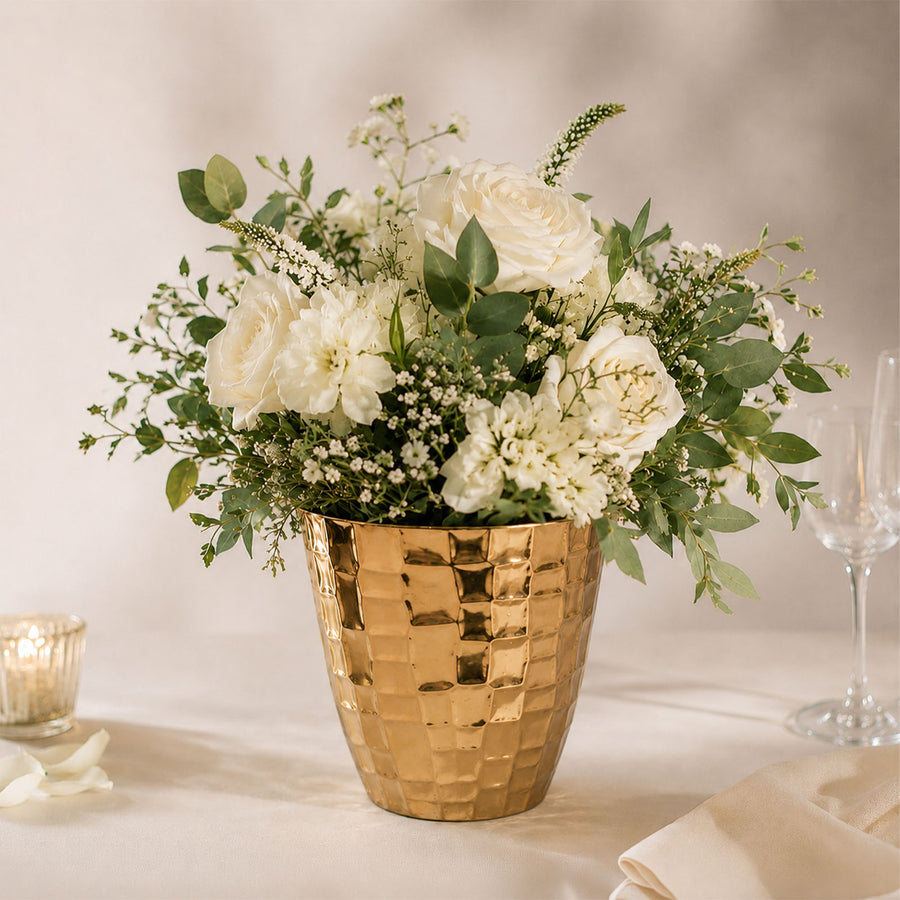White rose floral arrangement in a gold vase with green eucalyptus greenery