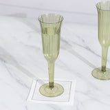 Green ribbed champagne flutes on a marble surface