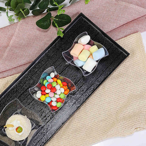 Black tray with clear bowls of candy and marshmallows