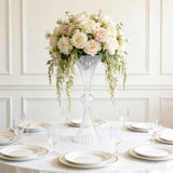 Elegant floral centerpiece in a clear vase on a dining table setting.