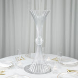 Elegant clear glass vase centerpiece on a dining table set for a formal meal.