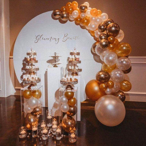 Dessert display under gold and white balloon arch
