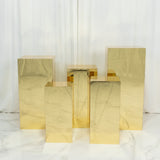 Five gold mirrored acrylic pedestal risers on marble floor and curtain backdrop