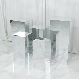 Set of mirrored display pedestals in various heights and shapes against a white backdrop.