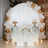 Elegant dessert display with gold and white balloons, cake stands, and candles.