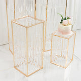 Elegant clear acrylic display pedestals with gold accents and floral cake decoration.