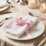 Elegant table setting with white napkin and pink ribbon on dinner plate
