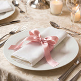 Elegant table setting with white plate, pink ribbon napkin, and candlelight