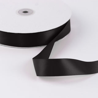 Black satin ribbon roll on white background, decorative craft ribbon