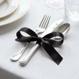 Elegant table setting with black ribbon tied around silver cutlery and utensils