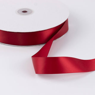 Red satin ribbon spool on white background