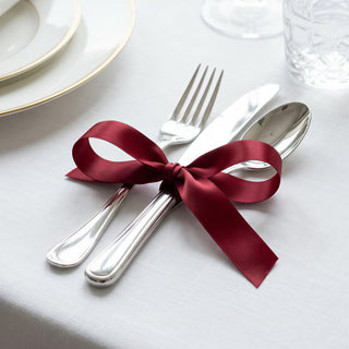 Elegant table setting with burgundy ribbon tied around silver cutlery