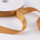 Gold satin ribbon spool on white background