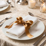 Elegant white napkin with gold ribbon on fine dining table setting