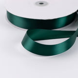 Dark green satin ribbon spool on white background
